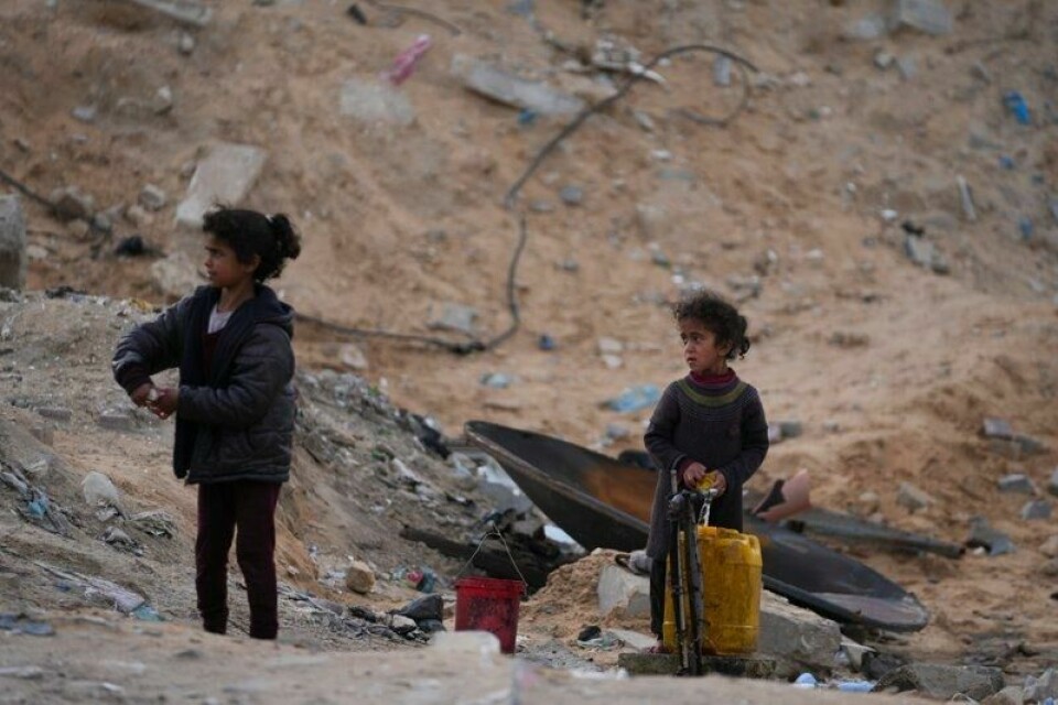 To palestinske jenter fyller en plastkanne med rent vann på en FN-drevet skole i Gaza by, der de nå bor. Bildet ble tatt søndag.
