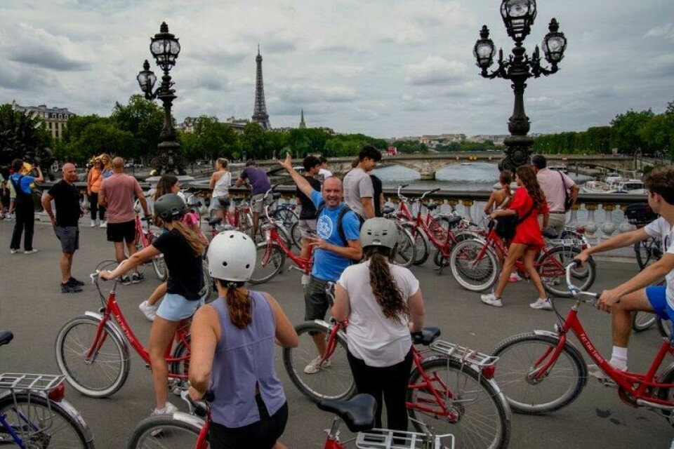 Turister på guidet sykkeltur i Paris stopper på en av broene over Seinen, der de blant annet har utsikt til Eiffeltårnet. Søndag stemte et klart flertall for å gjøre ytterligere 500 av byens gater bilfrie. Arkivfoto: Christophe Ena / AP / NTB