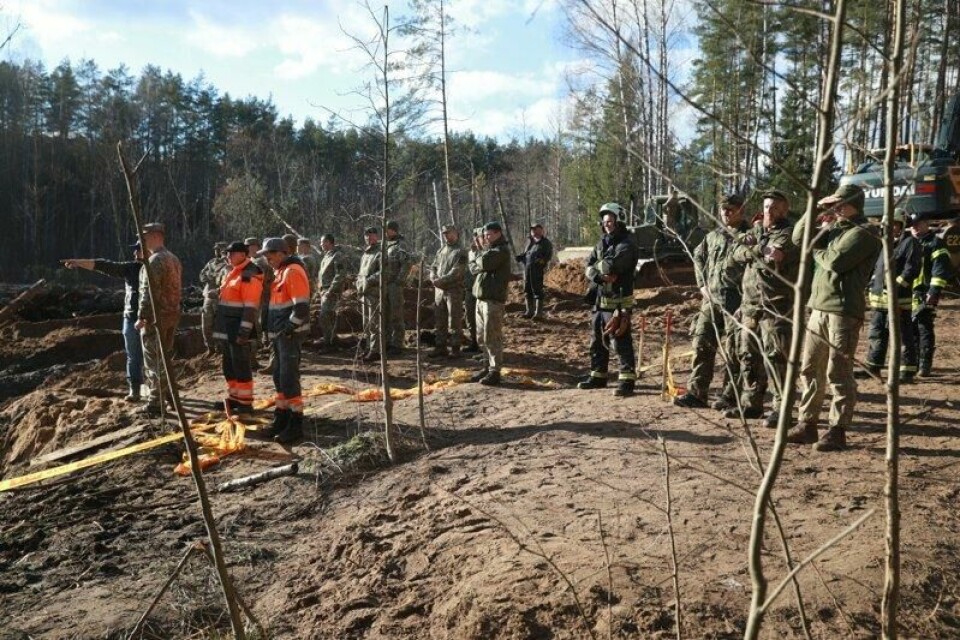Bergingsmannskaper diskuterer hvordan de skal hente opp det pansrede kjøretøyet som sank i ei myr under en øvelse i Litauen. Mandag meldes det at tre av de fire savnede soldatene er funnet døde.
