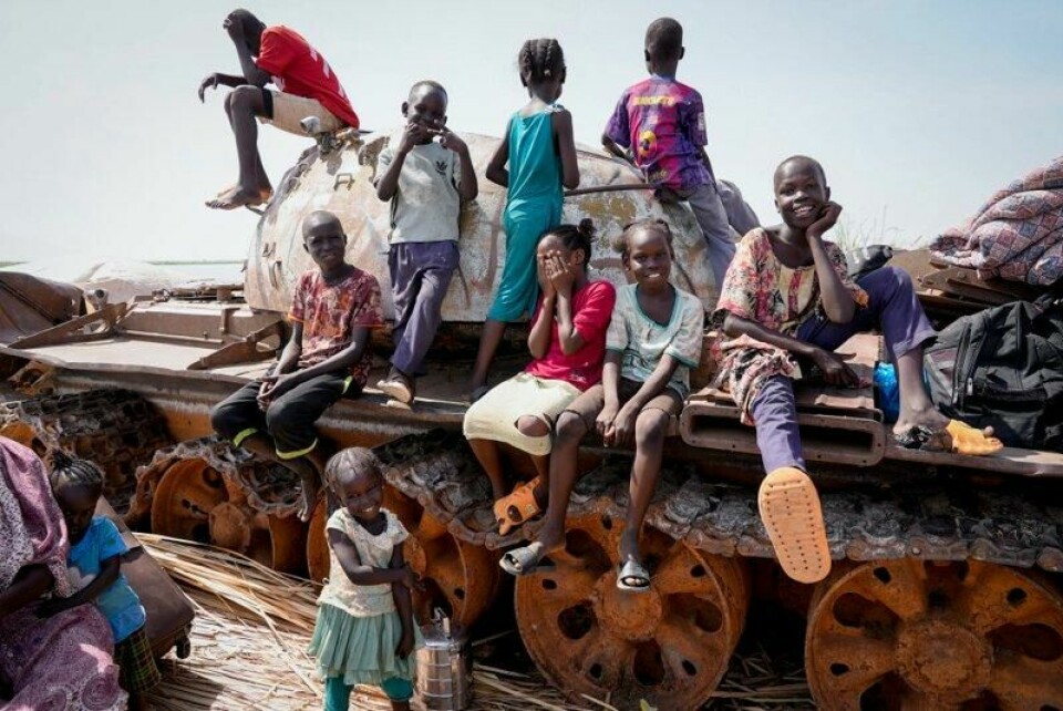 Barn leker oppå en utbrent stridsvogn i Sør-Sudan i 2023.