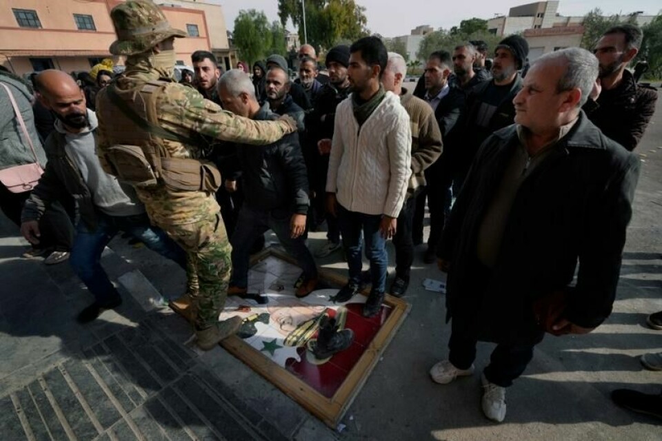 Tidligere syriske regjeringssoldater tråkker på et bilde av ekspresident Bashar al-Assad mens de står i kø og venter på å registrere seg og levere inn våpen for å få amnesti. Samtidig har Syrias nye makthavere pågrepet flere hundre personer som anklages for å ha vært lojale mot Assad-regimet. Bildet er tatt 23. desember.
