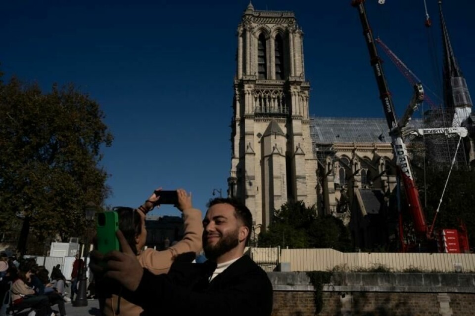 Turister fotograferer Notre-Dame-katedralen i Paris, som gjenåpner 7. desember. I fremtiden kan de måtte betale for å komme inn.