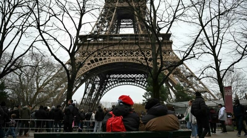 Visitors wait at the bottom of the Eiffel Tower as the site was closed and then reopened after a fire was reported in Paris, on December 24, 2024. (Photo by Anna KURTH / AFP)