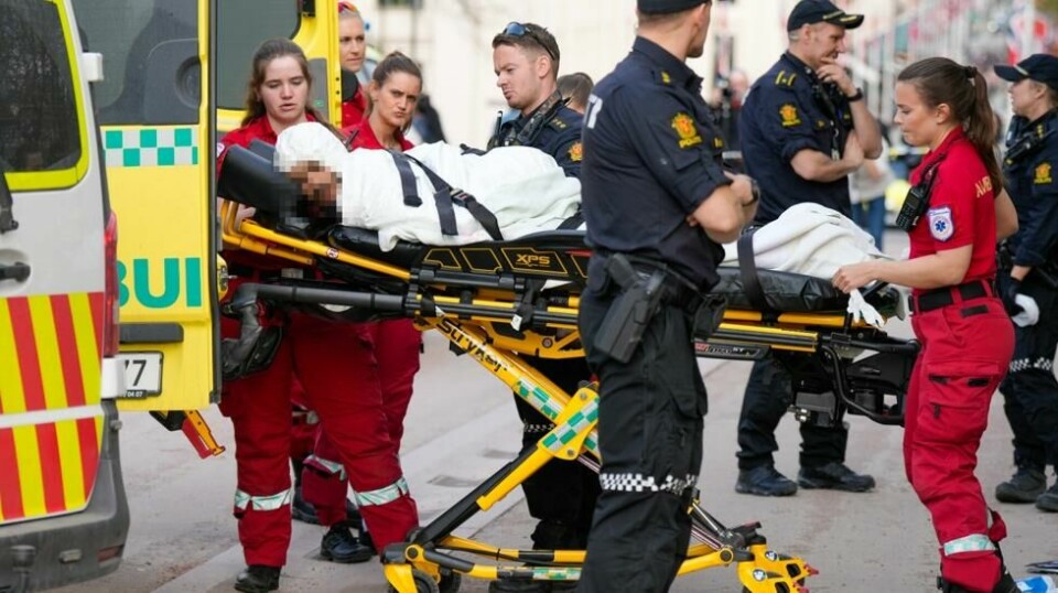 Mannen som ble pågrepet etter å ha løpt etter folk med to kniver i Oslo sentrum onsdag ettermiddag føres inn i en ambulanse. En person behandles for stikkskader i en arm. Foto: Heiko Junge / NTB