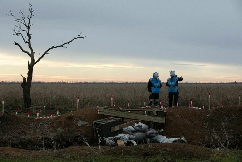Dagens ryddejobb er snart over, men det gjenstår enorme flater som må finkjemmes før lokalbefolkningen kan ta området i bruk. Her diskuterer lagleder Maksim Maksiuta (t.h) og en av hans team-medlemmer det videre arbeidet ved skyttergravene som omgir det enorme åkerlandskapet. Dagens ryddejobb er snart over, men det gjenstår enorme flater som må finkjemmes før lokalbefolkningen kan ta området i bruk. Her diskuterer lagleder Maksim Maksiuta (t.h) og en av hans team-medlemmer det videre arbeidet ved skyttergravene som omgir det enorme åkerlandskapet. Foto: Espen Røst / Panorama nyheter