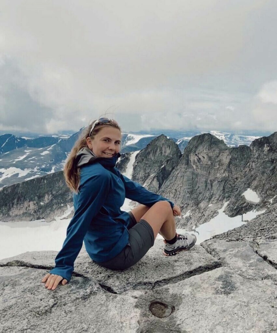 De senere årene har Sommerfelt Ovenstad sin lidenskap for fjellvandring bare vokst, og om vinteren finner man henne ofte på toppen av fjellene med randonee-ski på beina. Bilde av Runa Sommerfelt Ovenstad på toppen av et fjell på Offersøykammen i Lofoten. Smilende mot kamera i en rosa te-skjorte og med en vakker solnedgang i bakgrunnen. Runa forteller hva du må ha på pakkelisten når du skal på fjelltur i sommer i tillegg til å dele sine beste tips og favoritt-fjellturer i Norge.