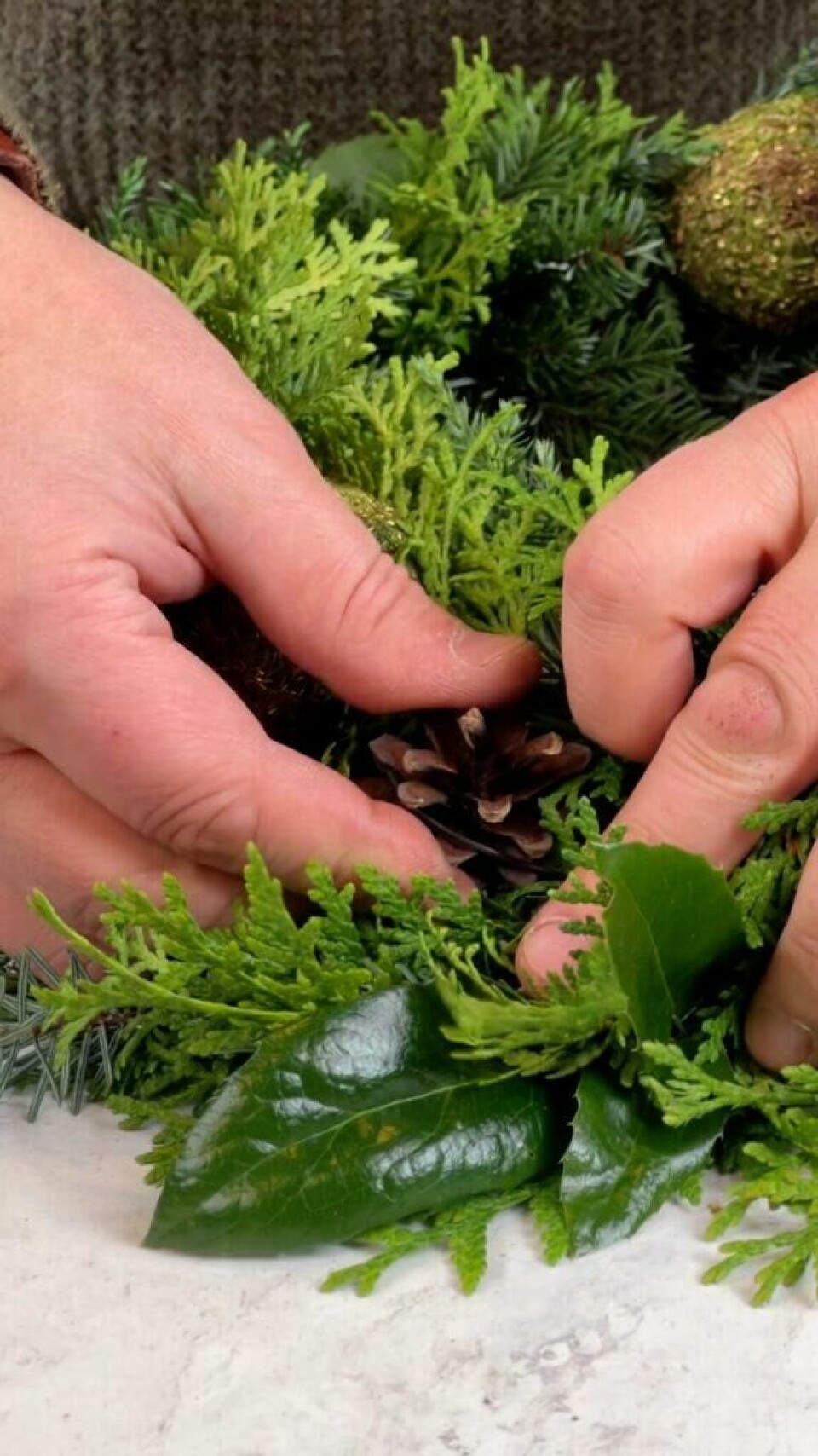 Å lage en egen julekrans er enklere enn du tror! Blomsterdekoratør Espen Skarphagen viser deg, steg for steg. Bilde av julekrans og hendene til Espen Skarphagen som viser frem innholdet i Kreative Ideer sin julekrans. Denne kan du lage selv og vi viser deg hvordan du lager den flott diy-julekransen!