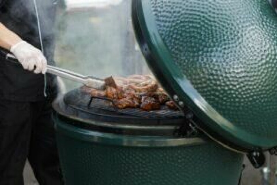 Kullgrill: En god kullgrill er et must for mange grill-entusiaster. Kullgrill best i test: Bilde av en person som steker kjøtt i en kullgrill