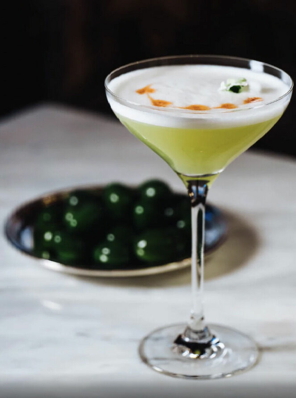 Om du ikke bor her, så gå innom hotellet for en cocktail i baren. (Foto: Hotels.com) Grønn cocktaildrink på hvitt marmorbord på hotell i Stockholm.
