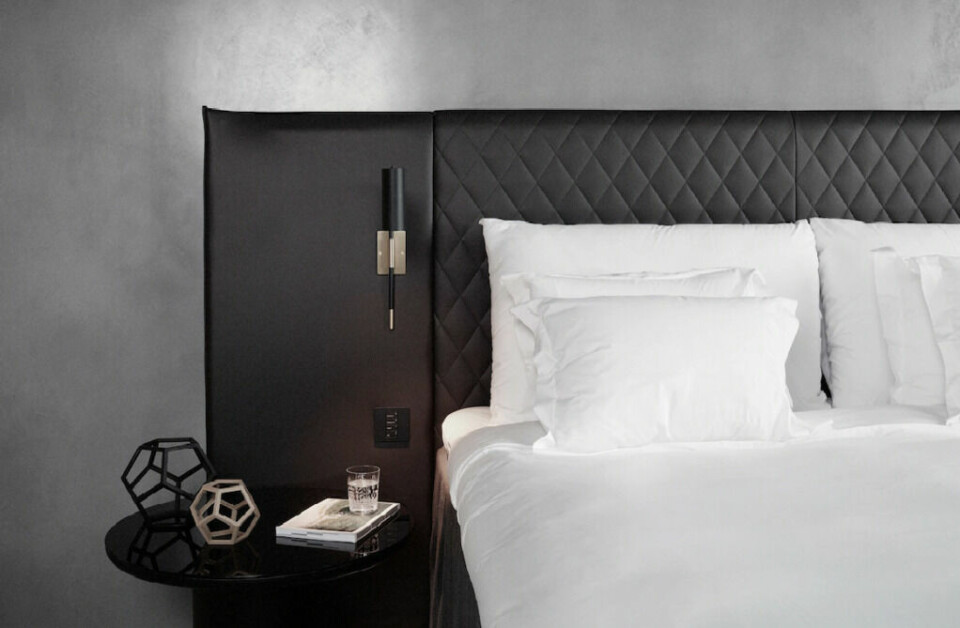 På hotellet At Six i Stockholm ligger alt til rette for en god natts søvn. (Foto: Hotels.com) Dobbeltseng med mørk sengegavl i skinn, nattbord og hvitt sengetøy på hotell i Stockholm.