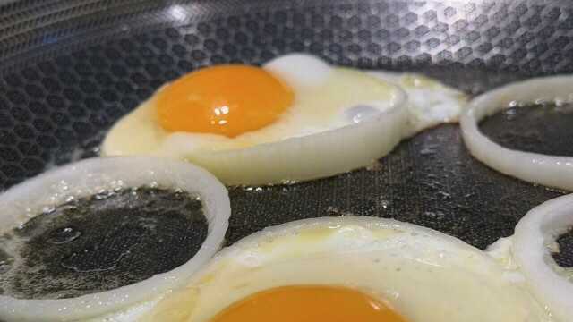 Stekte egg i løkringer – en smakfull og enkel vri på frokosten! Tilberedt på en høykvalitets stekepanne med bikubemønster som sikrer perfekt steking hver gang.