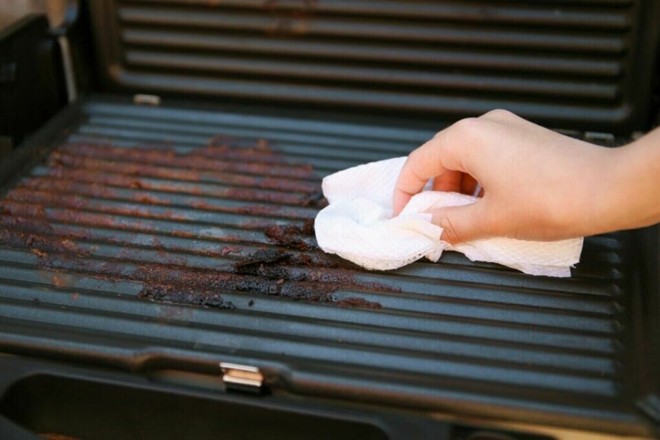 Vaske grill: Skitten grill? Slik får du den skinnende ren igjen! (Foto: Colourbox) Vaske grill: En person vasker grill med en klut.
