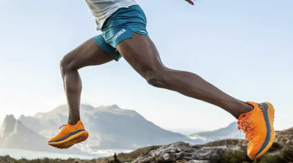 Hoka One One er en kjent og kjær favoritt blant turglade nordmenn. (Foto: Anton Sport) Bilde av Orange Hoka Sneakers. På bilde ser vi en atletisk man på løpetur med våres nyheter på bena