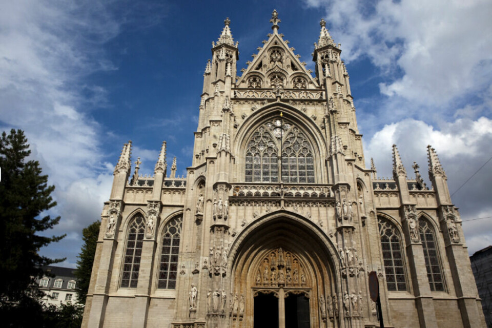 Église Notre-Dame du Sablon, en imponerende gotisk kirke i Brussel, Belgia. Kirken, som dateres tilbake til det 15. århundre, ligger i Sablon/Zavel-distriktet, som er kjent for sine antikvitetsbutikker og marked, restauranter og sjokoladebutikker. (Foto: Canva) Dette bildet viser Église Notre-Dame du Sablon, en imponerende gotisk kirke i Brussel, Belgia. Kirken, som dateres tilbake til det 15. århundre, er kjent for sin vakre flamboyante gotiske arkitektur, detaljrike fasade og store, intrikate glassmalerier. Den ligger i det elegante Sablon-området, som er kjent for sine antikvitetsbutikker, kunstgallerier og sjokoladebutikker. Kirkens fasade er rikt dekorert med utskårne steinstatuer og spisse buer, mens den store hovedportalen har en intrikat treskåret dør. På toppen av bygningen ses spisse spir og delikate ornamenter som er typiske for gotisk arkitektur. Église Notre-Dame du Sablon regnes som en av de vakreste kirkene i Brussel og har historisk vært et viktig pilegrimsmål. I dag er den en populær attraksjon både for troende og arkitekturinteresserte besøkende.