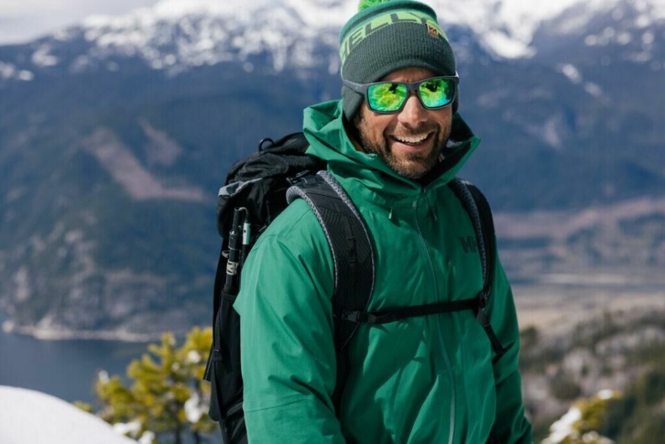 Skalljakkene kjendisene fra 71 grader nord har på seg kan du bruke året rundt med ulike mellomlag under. (Foto: Helly Hansen) Bilde av mann i grønn skaljakke med solbriller og sekk på toppen av et fjell med en fjord i bakgrunn. Vi forteller hvilke klær deltakerne i 71 grader nord har på seg i årets (2023) og programmets 15. sesong av programmet.