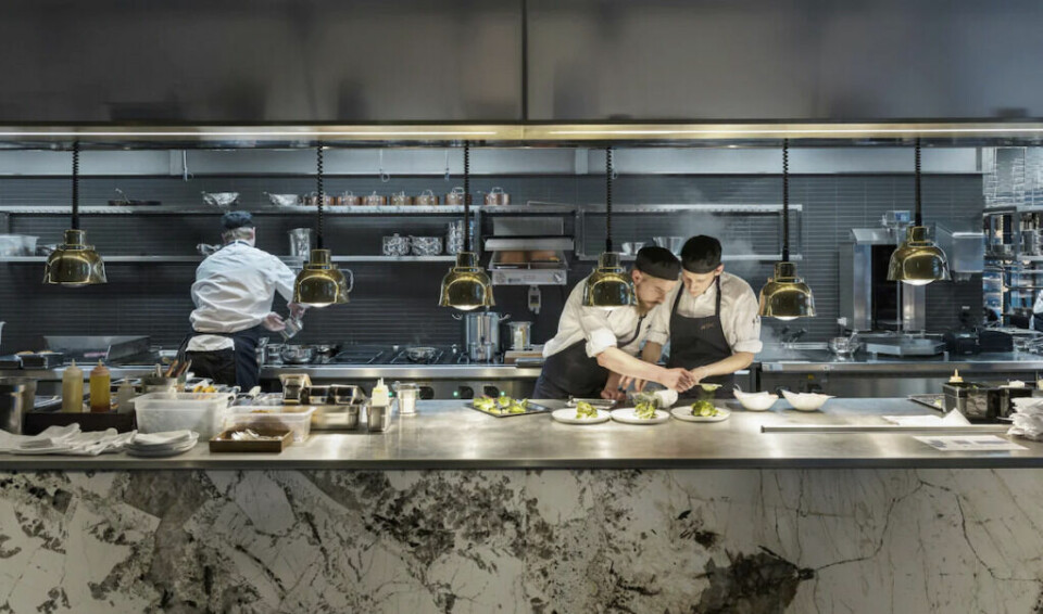 At Six er et moderne femstjerners hotell i Stockholm sentrum. (Foto: Hotels.com) To kokker som lager mat på stor kjøkkenbenk på hotell i Stockholm.