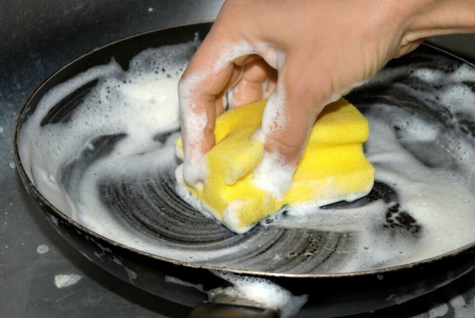 Vaske med såpe: Dette må du ikke gjøre med en stekepanne i karbonstål etter bruk. (Foto: Colourbox) Stekepanne i karbonstål: Person vasker en stekepanne med såpe og svamp.