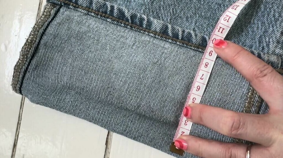 Mål opp hvor mange centimeter jeansen skal legges opp, (Foto: Kreative Ideer/ Miriam Schjetlein) Målebånd som holdes over et oppbrettet buksebein.