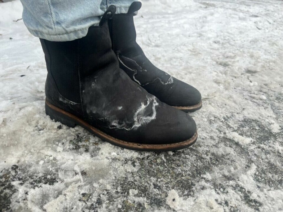Saltflekker på skoene er aldri et kjekt syn, men det finnes råd! Her viser vi deg hvordan du fjerner salflekker fra sko, skinnsko og sko i semsket skinn. Bilde av sko med saltflekker etter vinterens veisalting. Skoene er svarte skinnsko og de har en veldig tydelig saltrand. Personen som har skoene på har også på seg en dongeribukse og står ute på en snødekket asfalt. Vi forteller hvordan du selv kan fjerne salt fra skoene dine.
