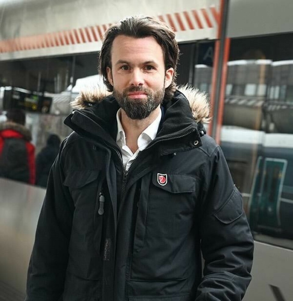 Juridisk seniorrådgiver i Forbrukerrådet, Thomas Iversen, forklarer hva standardkompensasjon er. Bilde av en mann som står på en togstasjon, han har mørkt hår og sjeggvekst og står i en tykk sort parkas. Vi har snakket med juridisk seniorrådgiver i Forbrukerrådet, Thomas Iversen, som forklarer alt du må vite om standardkompensasjon.