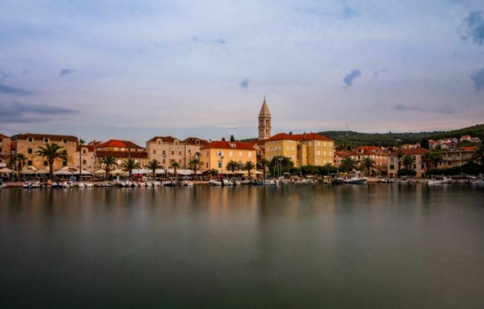 Hovedbyen på øya Brač er Supetar, og her kan du finne alt fra vakre strender til restauranter og kafeer. (Foto: Colourbox) Bilde som er tatt fra kysten og inn mot hovedbyen på øya Brac i Kroatia. Supetar bader i gyllent sollys og på bildet ser du klassiske murbygg med røde tak. Vi forklarer hva du må se og gjøre på Brac, som ligger utenfor Split i Kroatia, samt hjlper deg med å finne billige reiser til Brac, hvorav restplasser er populære.