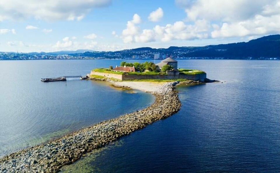 Kort båttur fra sentrum: Her er det muligheter for soling og bading. (Foto: Canva) Munkholmen i Trondheimsfjorden i solskinn