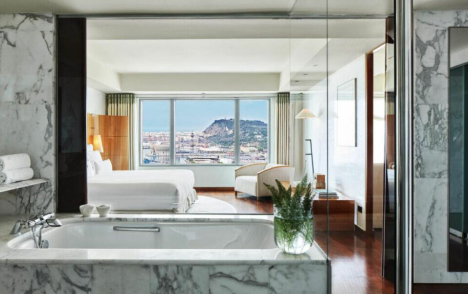 Hotel Arts er et femstjernes luksushotell med svært smakfulle rom. (Foto: Booking.com) Hotellrom med badekar i marmor og dobbeltseng på luksushotell.