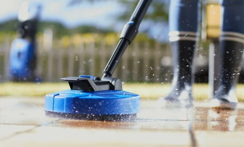 Vedlikehold av terrassen er viktig for at den skal kunne vare lengst mulig uten skader. Vi forteller deg hvordan du vasker terrassen på best mulig måte. (Foto: Staypro) Person som bruker en blå terrassevasker på uteområdet for å vaske terrassen. Vi gir deg gode råd på hvordan du vedlikeholder terrassen på best mulig måte.