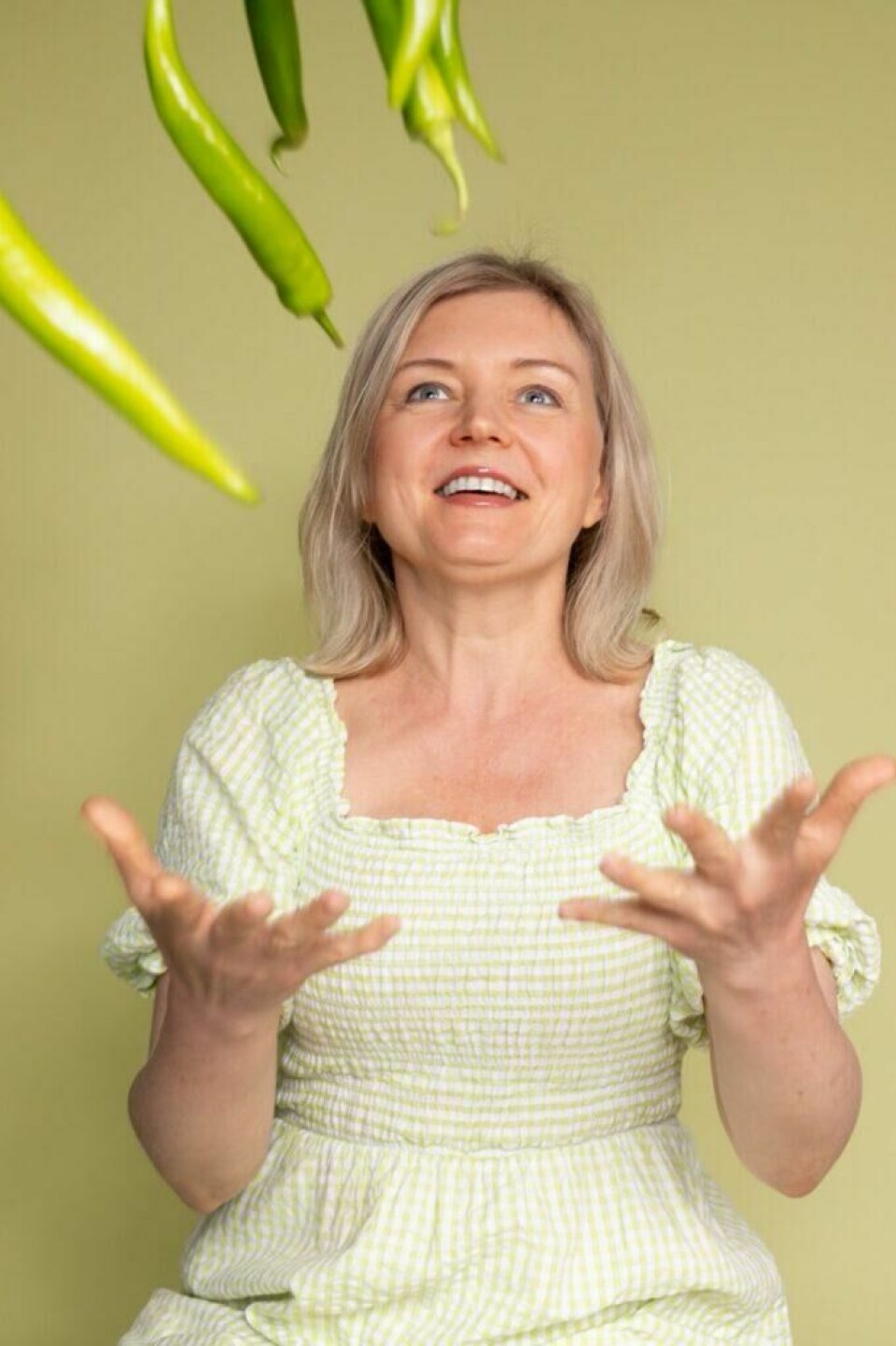 Hvor mye proteiner trenger man egentlig i løpet av en dag. Vi forhørte oss med overlege Tanja Kalchenko! Bilde av overlege Tanja Kalchenko i en grønnrutete kjole som kaster jalapeños i været mens hun smiler foran en grønn bakgrunn. Kalchenko gir oss svaret på hvor mye proteiner vi egentlig trenger hver dag? Hva som skjer om man ikke spiser nok og hva som skjer om man spiser for mye proteiner.