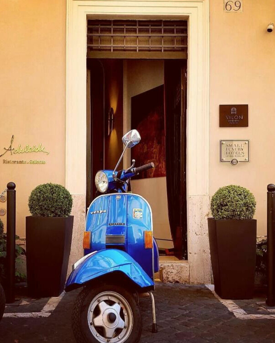 Hva gir vel bedre følelse enn å suse rundt i Romas gater på en scooter, akkurat slik som italienerne gjør. Blå scooter utenfor hotellinngang i Roma i Italia.