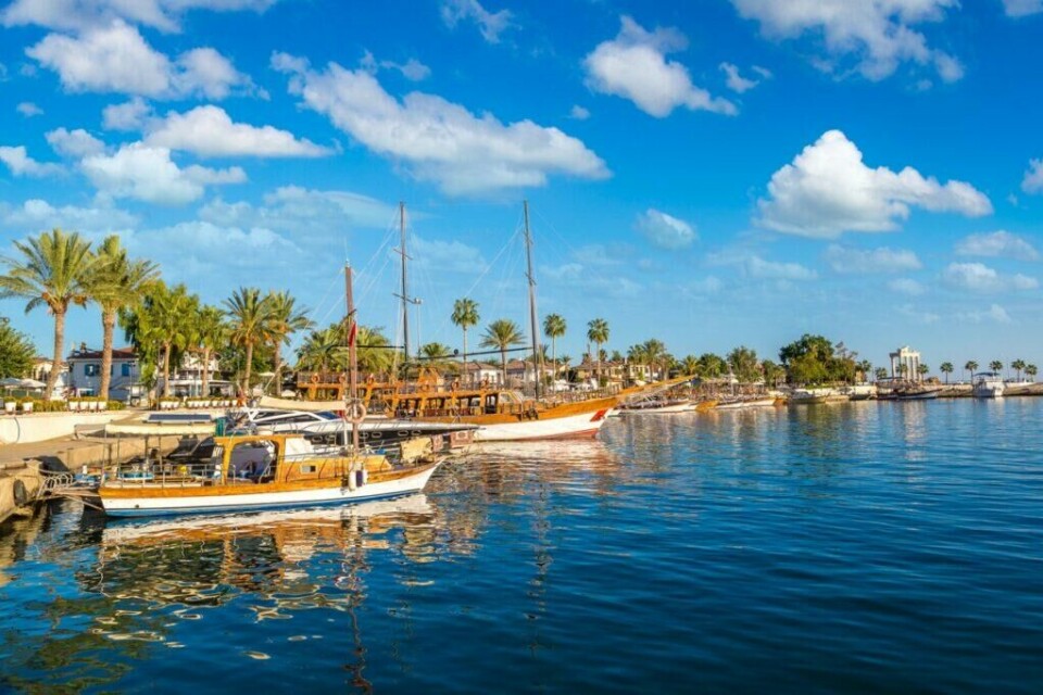 Side i Tyrkia er en populær destinasjon for de som ønsker en familievennlig strandferie. Byen ligger mellom Antalya og Alanya. (Foto: Colourbox) Bilde av promenaden i Side i Tyrkia. Her ser du blått hav og båter som ligger i solen langs promenaden. Vi hjelper deg med å finne den beste reisen til Tyrkia for deg ved å fortelle om hva du kan gjøre i blant annet Antalya, Side og Alanya.