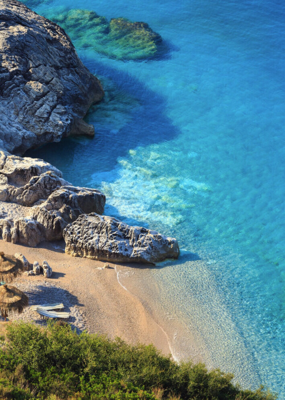 – Her er det litt dyrere enn Polen, men fortsatt veldig mye billigere enn de typiske charter-stedene, forteller Lange om Albania. Dette bildet viser en naturskjønn strand i Albania, omgitt av krystallklart turkisblått vann, dramatiske klippeformasjoner og gyllen sand. Detaljbeskrivelse: Den lille sandstranden ligger skjult mellom klipper, noe som gir en følelse av eksklusivitet og ro. Det klare vannet viser undervannssteinene tydelig, med forskjellige nyanser av blått og grønt. Bølger skaper myke mønstre i sanden, og en liten robåt ligger trukket opp på land, noe som gir en autentisk og uberørt følelse. Stråparasoller og busker i forgrunnen gir et inntrykk av en avslappende og naturlig atmosfære. Bildets budskap: Dette bildet fremhever Albanias skjulte perler og vakre kystlinje, perfekt for de som søker en budsjettvennlig ferie med fantastiske strender og krystallklart vann. Et ideelt reisemål for de som vil unnslippe turistmassene og nyte en uforstyrret strandopplevelse. – Her er det litt dyrere enn Polen, men fortsatt veldig mye billigere enn de typiske charter-stedene, forteller Lange om Albania.