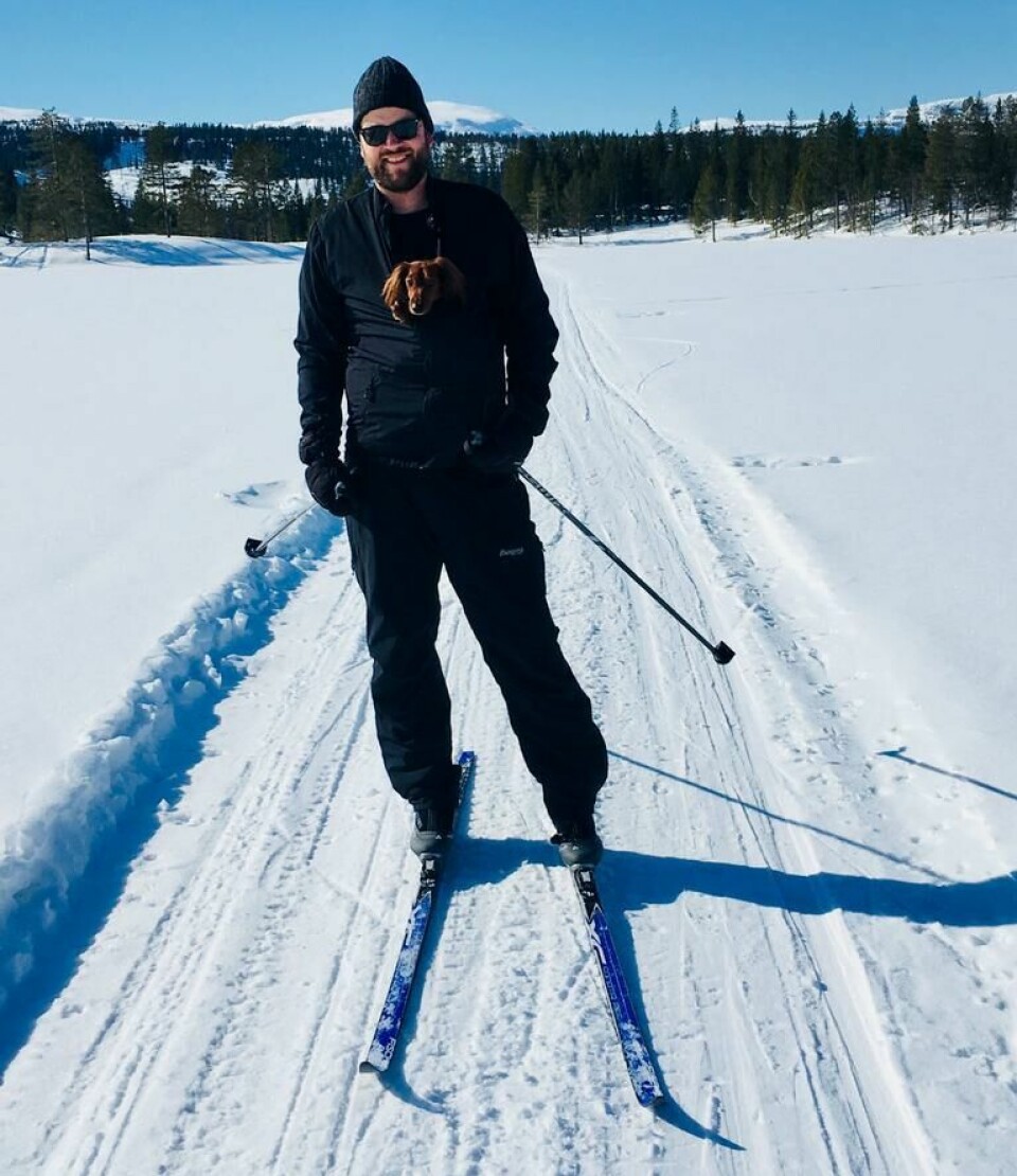Ove Barlund på skitur sammen med Vita, en fire år gammel dvergdachs-tispe, som nyter utsikten fra en lomme på brystet. (Foto: Ove Barlund / Privat) Mann på ski med hund i sekk på magen.