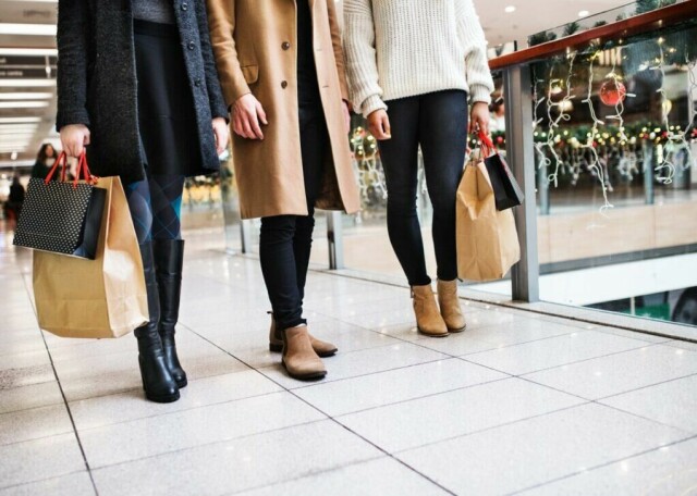 Tre stilige personer nyter en dag med julehandel, bærende på handleposer fylt med gaver. Med vinterklær og et julepyntet kjøpesenter som bakgrunn, er dette et perfekt bilde på travle førjulsdager. (Foto: Colorbox)