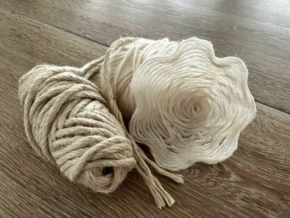 To nøster garn ved siden av en dekorativ drikkebrikke laget av garn og lim. (Foto: Kreative Ideer/ Aurora Lange) Et nærbilde av to garnnøster, ett naturlig brunt og ett hvitt. En spiralformet garnbrikke med bølgete kanter ligger ved siden av nøstene på et tregulv. Garnbrikken har en myk tekstur og fremhever det håndlagde preget av materialene.