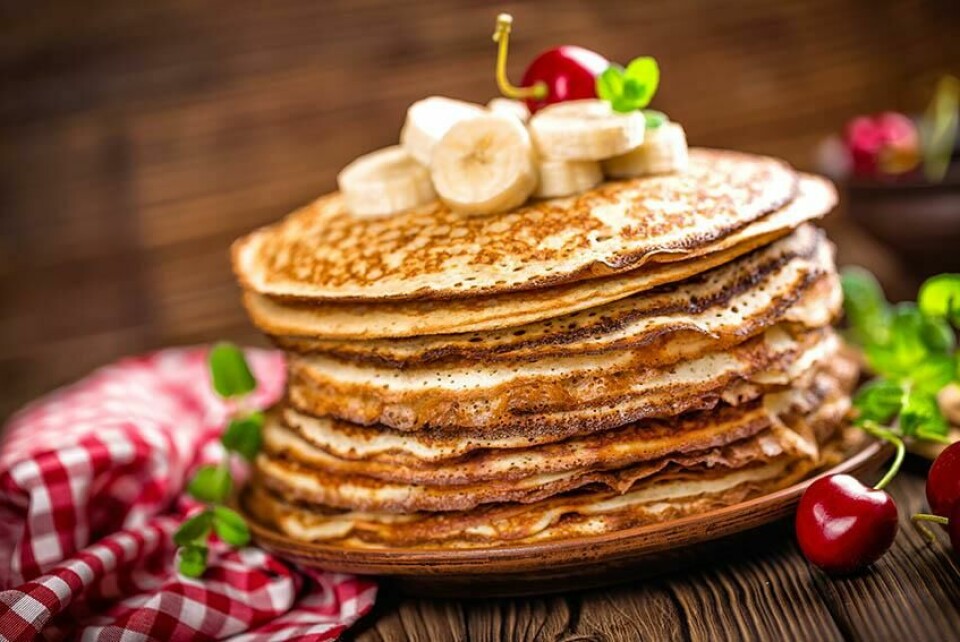 Finnes det noen bedre helgefrokost enn bananpannekaker? Når bananer tilsettes amerikanske pannekaker blir de søtere og saftigere. (Foto: Colourbox) pannekaker med banan servert i en stack med bananer på toppen står på et brunt bord bananpannekaker banana pancakes