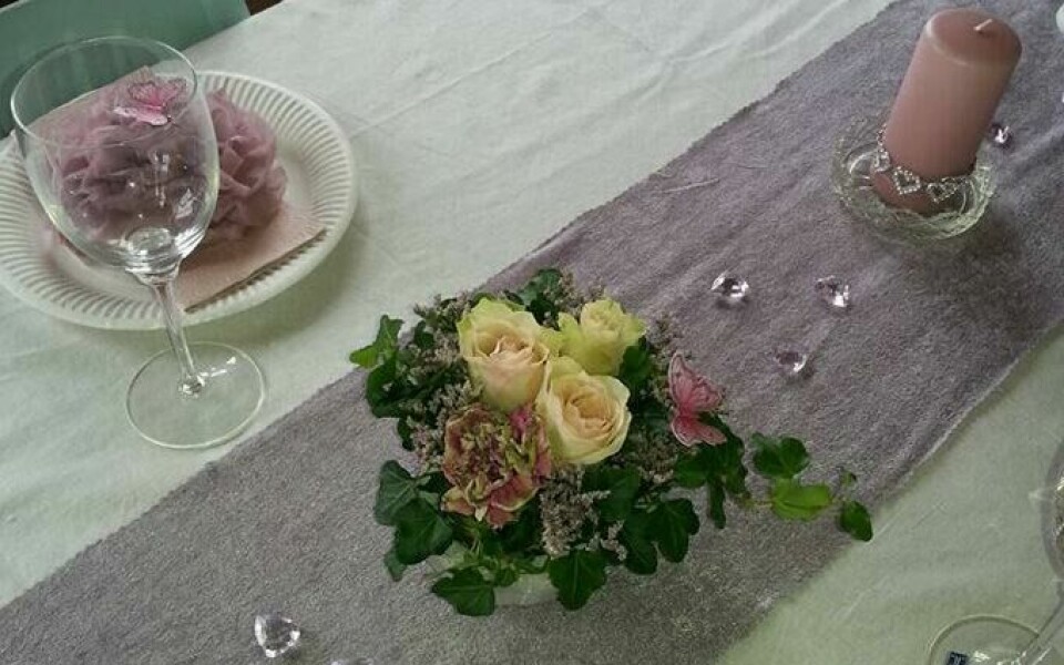 Rosa går igjen i bprddekkingen i både duk, servietter, lys, dekor og blomster. (Foto: Wenche Gullstein Rian / privat) Nærbilde av flott borddekking med rosa til konfirmasjon. Bord dekket med hvit duk, servise og rosa detaljer på lys, servietter og pynt. Midt på bordet og i bildet er det en bukett med hvite roser og rosa blomster.