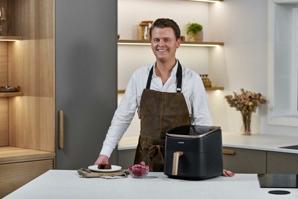 Matformidler Simen Vatne, som har spesialisert seg på bruk av airfryer og skrevet kokeboken 'Norsk mat med airfryer', deler sine beste tips for å utnytte airfryeren til fulle. (Foto: Foodie.no) En mann står på kjøkkenet med en Cosori airfryer på kjøkkenbenken. Han smiler og har på seg et forkle.