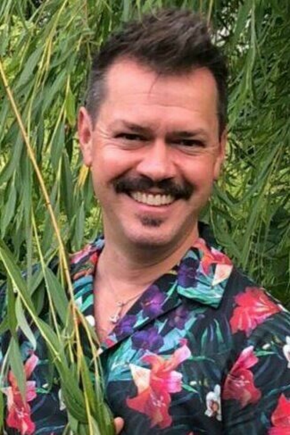 Espen Skarphagen er hageekspert og blomsterdekoratør. Han står bak bloggen skarpihagen.no , der han deler sine eksperttips rundt hage, uterom og blomster. Bilde av Espen Skarphagen med stort smil og i i blomstrete skjorte i hagen sin.