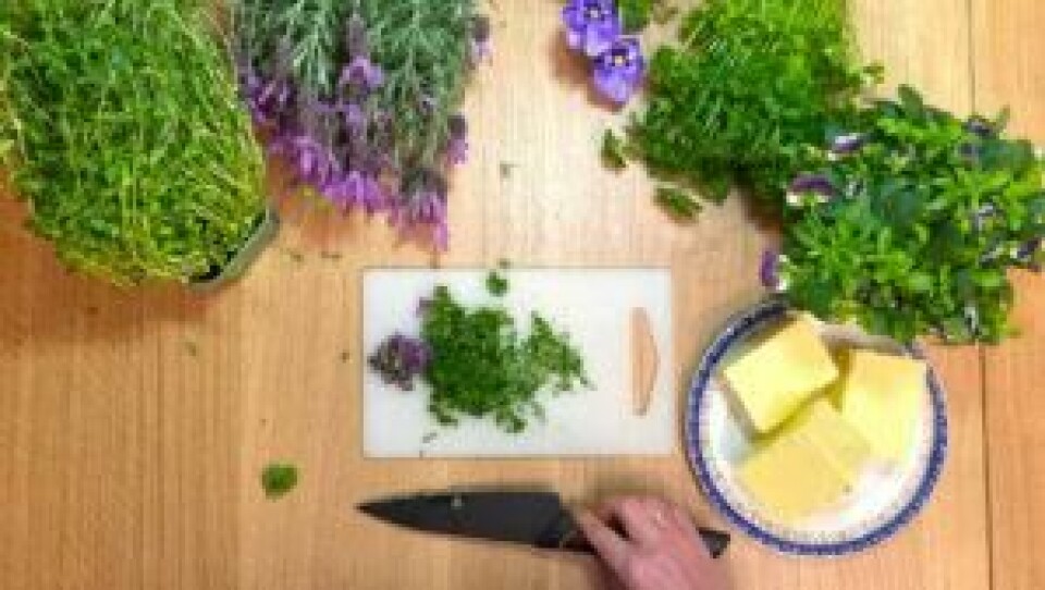 Det finnes et stort utvalg blomster som kan spises. Det viktigste å huske på er at de ikke er blitt utsatt for sprøytemidler. Blomster og urter kuttet opp på et skjærebrett. Skål med smør ved siden av.
