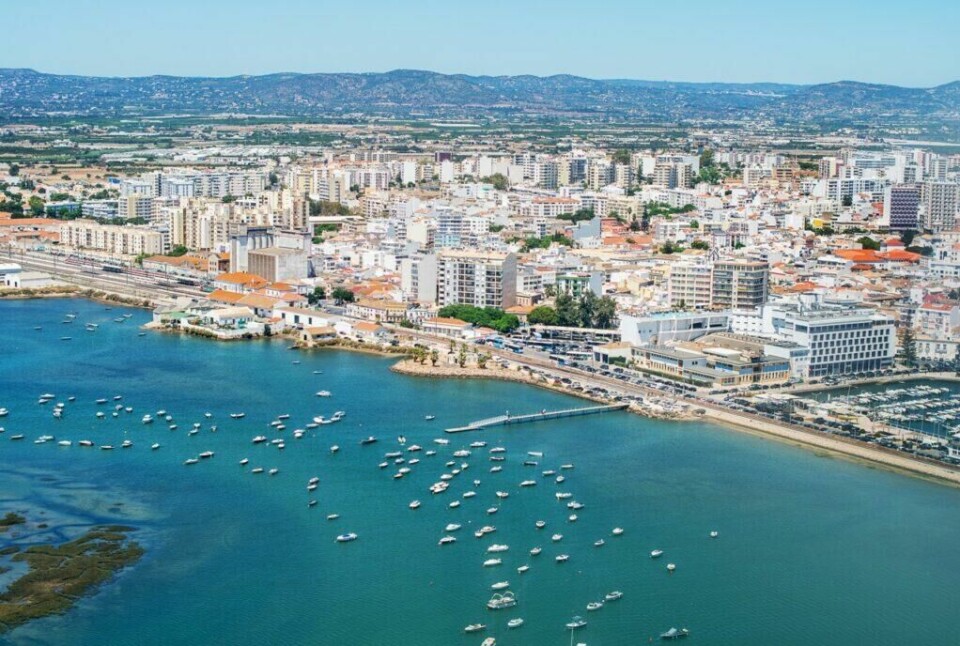 Sjekk ut vakre den vakre byen Faro som også regnes som hovedstaden langs Algarvekysten. (Foto: Colourbox) Bildet viser byen Faro langs Algarve-kysten i Portugal. Det er en oversikt over byen med mange bygninger, inkludert høye leilighetskomplekser og lavere bygninger nær vannkanten. Foran byen ligger en bred havn med mange små båter ankret opp i det blågrønne vannet. I bakgrunnen kan man se det landlige landskapet og åsene som omgir byen. Vi hjelper deg med å planlegge ferien til Algarve-kysten i Portugal. Vi gir deg alt fra tips til byer; Lagos, Faro, Tavira, Albufeira og Sagres. Samt hvor du kan finne hotell langs Algarve-kysten og shoppingmulighetene.