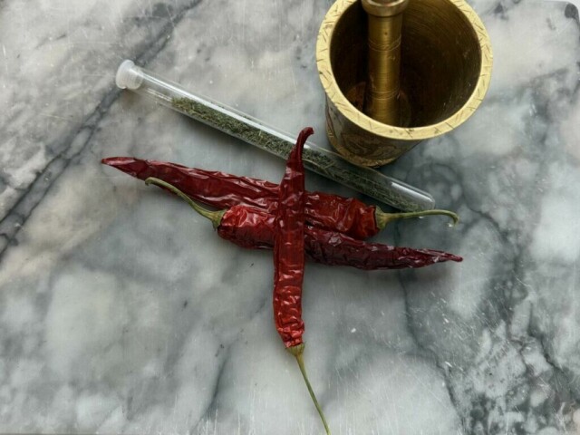 Tørkede chili, urter og en klassisk messingmorter – essensielt for autentisk krydderblanding. (Foto: Kreative Ideer/Aurora Lange)