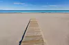 Bildet viser en bred sandstrand med en treplatting som leder ut mot havet. Stranden er urørt og rolig, med fin, lys sand som strekker seg ut i begge retninger. Havet i bakgrunnen har en klar blåfarge, med små bølger som forsiktig skyller inn mot kysten. Himmelen er lys blå med noen få spredte skyer, noe som gir en følelse av en varm og solrik dag. Dette kan være en av de mest solrike strendene i Europa, og er sannsynligvis i Alicante, Spania, kjent for sine lange strender og perfekte badeforhold. Har du lyst til å dra til en badestrand som er sikret sol og fint vær? Vi tok en titt på listen som viser byene med flest soltimer i gjennomsnitt i måneden. For hver solrike by har vi funnet frem stranden reisende kårer til den fineste. Under finner du altså et utvalg på 5 strender i 4 forskjellige land (spania, italia, frankrike og Hellas), som alle kan skimte med mye sol.
