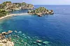 Bildet viser den vakre Isola Bella, en av de mest ikoniske strendene på Sicilia, Italia. Øya ligger like utenfor kysten av Taormina, og er forbundet med fastlandet via en smal sandbanke, som blir synlig avhengig av tidevannet. Havet rundt Isola Bella har en praktfull blåfarge, med krystallklart vann hvor steinformasjoner og havbunnen er tydelig synlige. Mange små båter flyter i bukten, og stranden er omgitt av dramatiske klipper og frodig vegetasjon. Dette er en av de mest populære bade- og snorklestedene på Sicilia, kjent for sitt marine liv, naturlige skjønnhet og postkortlignende omgivelser. Isola Bella ligger ca. 55 km nord for Catania, noe som gjør den til en av de beste strendene nær byen for både lokalbefolkningen og turister. Har du lyst til å dra til en badestrand som er sikret sol og fint vær? Vi tok en titt på listen som viser byene med flest soltimer i gjennomsnitt i måneden. For hver solrike by har vi funnet frem stranden reisende kårer til den fineste. Under finner du altså et utvalg på 5 strender i 4 forskjellige land (spania, italia, frankrike og Hellas), som alle kan skimte med mye sol.