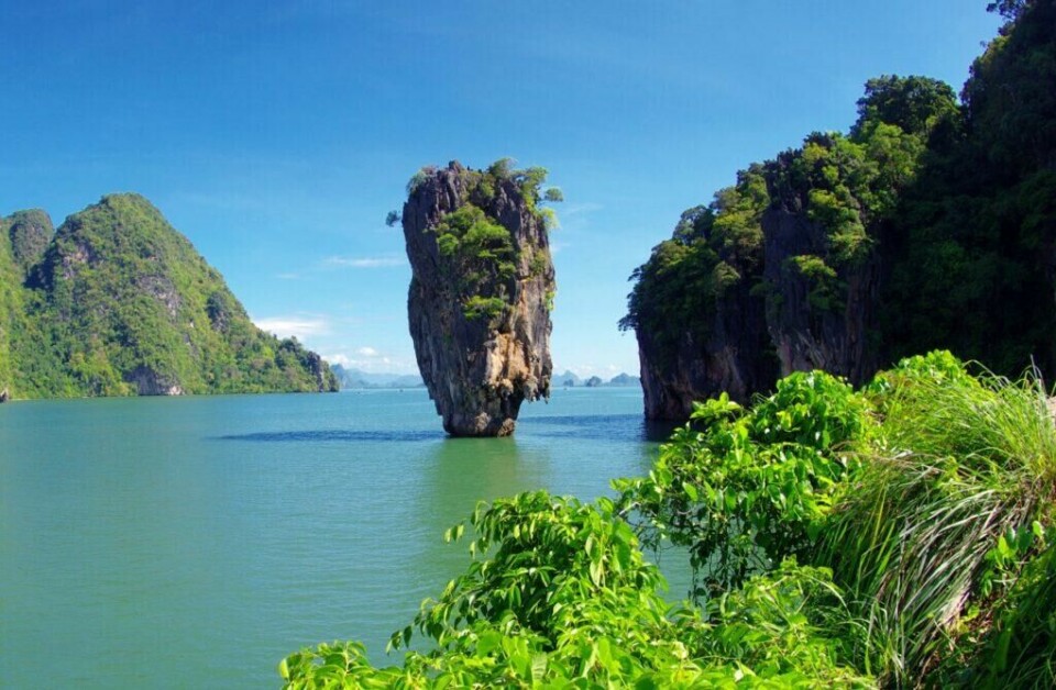 Phuket er en populær destinasjon å reise til i Thailand. Her kan du nyte blått hav og spektakulære kalkesteinsklipper, som blant annet disse som er kjent som en del av James Bond Island. (Foto: Colourbox) Et ikonisk kalksteinsfjell stiger opp fra det smaragdgrønne vannet i Phang Nga-bukten (også kjent som James Bond Island), omringet av frodige, grønne øyer og vegetasjon, med en klar blå himmel i bakgrunnen. Vi hjelper deg med å finne reise til Thailand, enten du vil ha billige reiser med restplasser, eller kanskje pakkereiser til de populære destinasjonene Phuket, Hua Hin og Krabi. Her finner du også hotell i Thailand.