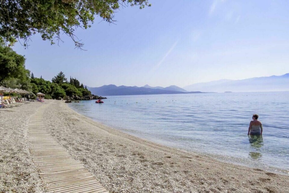 En tur til Lefkas er perfekt for deg som vil kjenne på det det ekte Hellas, eller som vil oppleve noen av de flotteste strendene de greske øyene kan tilby. (Foto: Apollo) Bilde fra sommerferie i syden på greske Lefkas. Bilde av kvinne på sandstrand med skinnende sol.