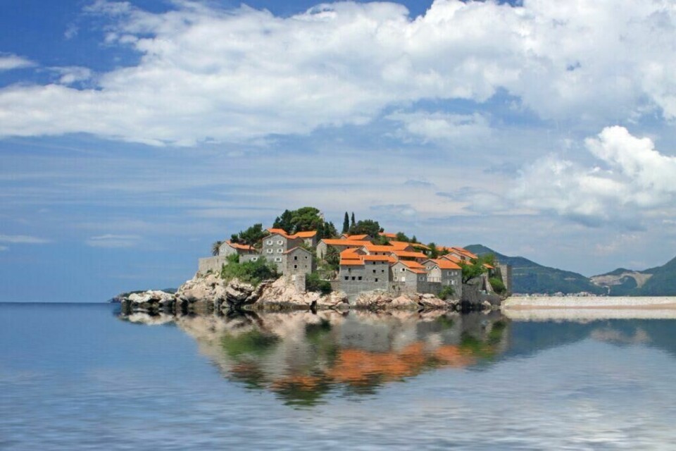 Sveti Stefan i Montenegro oser av luksus og er kanskje det mest fotograferte motivet i Middelhavs-landet. (Foto: Colourbox) Panoramautsikt over øya Sveti Stefan i Montenegro, med sine karakteristiske oransje taktegl på gamle steinbygninger. Øya er omgitt av klipper og reflekteres vakkert i det rolige havet. Over øya er en skyet himmel, som gir en dramatisk bakgrunn. Montenegro er et spennende land langs Middelhavet som er rangert til å være et billig land for nordmenn å feriere i. Vi hjelper deg med å finne pakkereiser som inkluderer fly og hotell, samt restplasser til Montenegro.