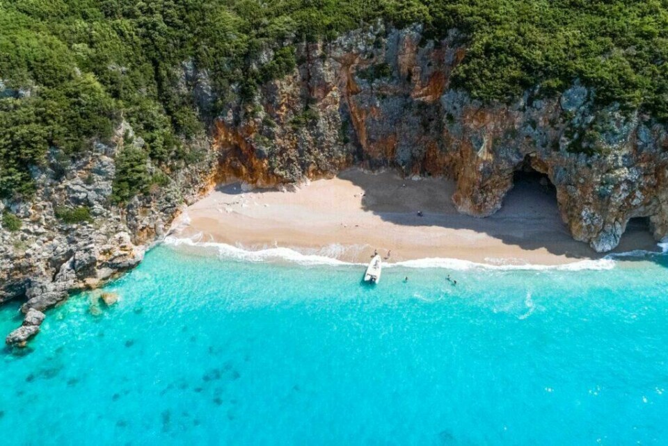 Albania ble kåret til 'det hotteste landet å besøke' i 2018 av reisemagasinet Vagabond. (Foto: Apollo) Bilde av vakker strand med båt i albania, syden hvor du kan booke din sommerferie