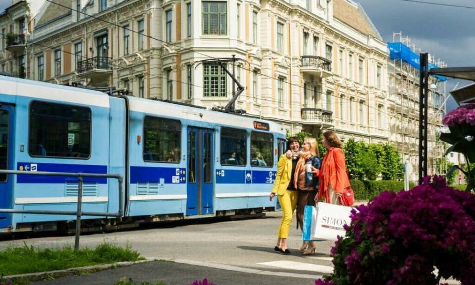Det skader ikke å ha full tilgang til kolletivtransport som går til alle kanter av byen når man for eksempel er på shoppingtur. (Foto: CH / VisitNorway) Smilende damer i Oslo foran trikk på shopping med handleposer i en av hovedstadens mange shoppinggater.