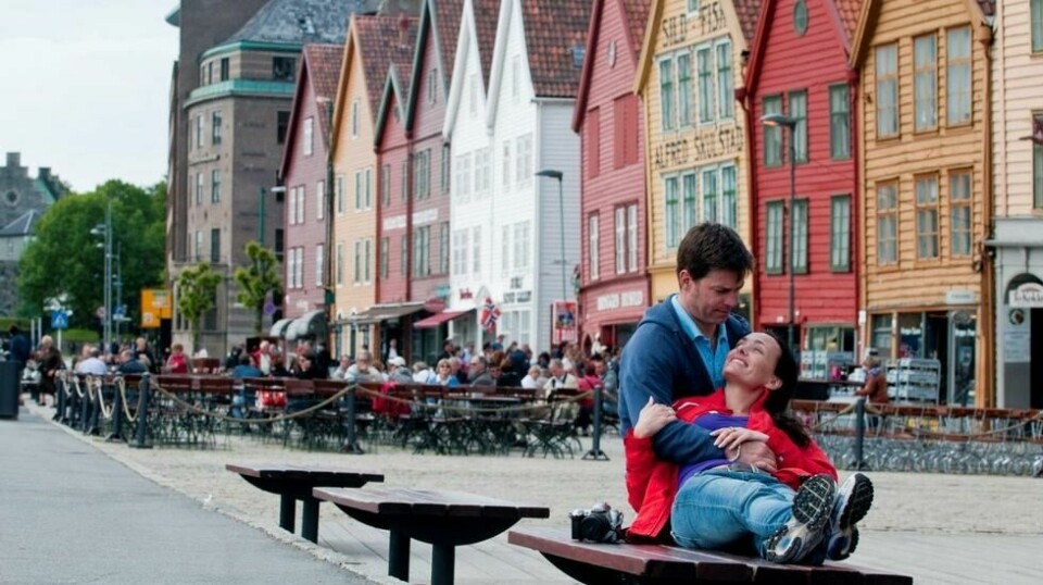 Bergen kan by på mange opplevelser for de som tar turen hit. (Foto: CH / Visit Norway) Par på benk på bryggen i Bergen.